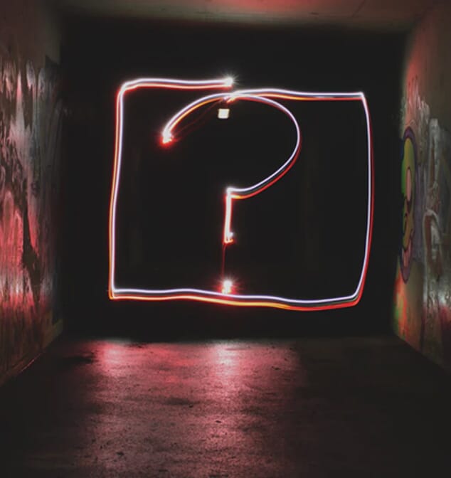 Why choose us image is a long exposure night time photo in a graffiti tunnel. A question mark is written in light.