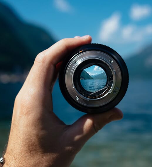 Resoscope. A camera lens looks into the distance of a lake between hills.