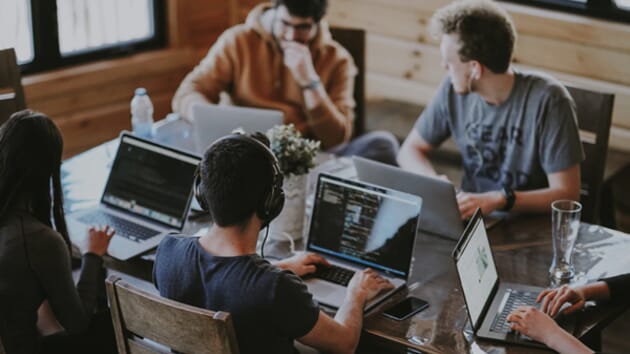 Marketing services in-housing. A group of people work at laptops in an office decorated in wood.