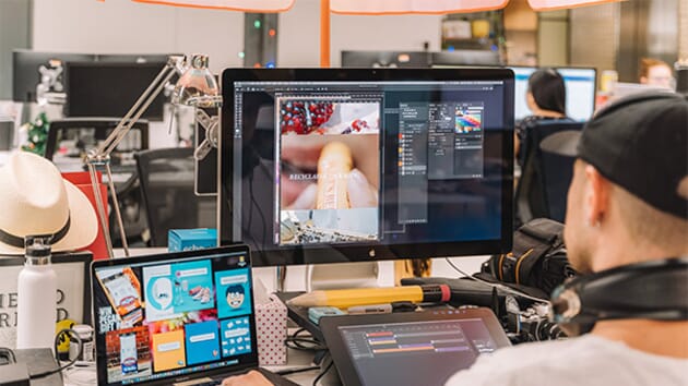 Digital Design Services. A person with a snapback hat is working on graphic art at their computer.